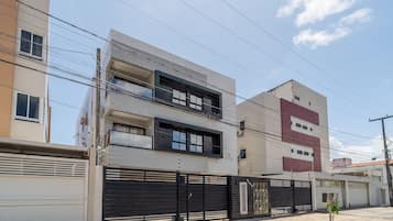 A multi-story building with a black gate, a visible window, and a clear sky.
