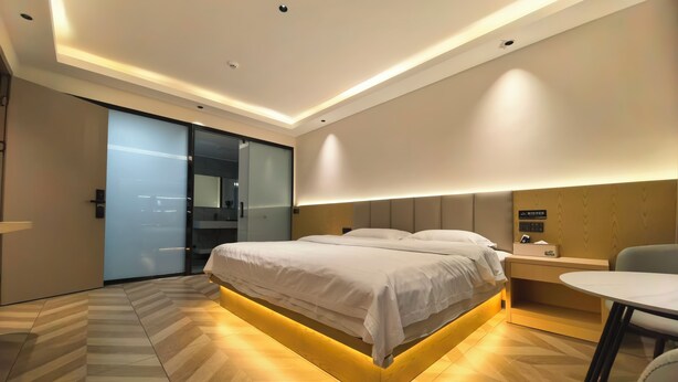 Een moderne hotelkamer met een groot bed, nachtkastje en een klein bureau met stoel.