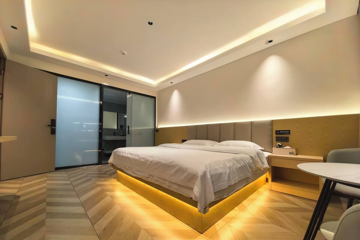 Une chambre d’hôtel moderne avec un grand lit, une table de chevet et un petit bureau avec une chaise.