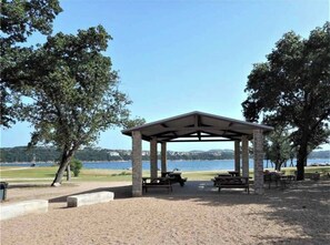 A covered picnic area with benches and tables, surrounded by trees and a view of a lake. - All Decked Out 3-bedroom townhome in gorgeous Point Venture with fantastic views (Point Venture)