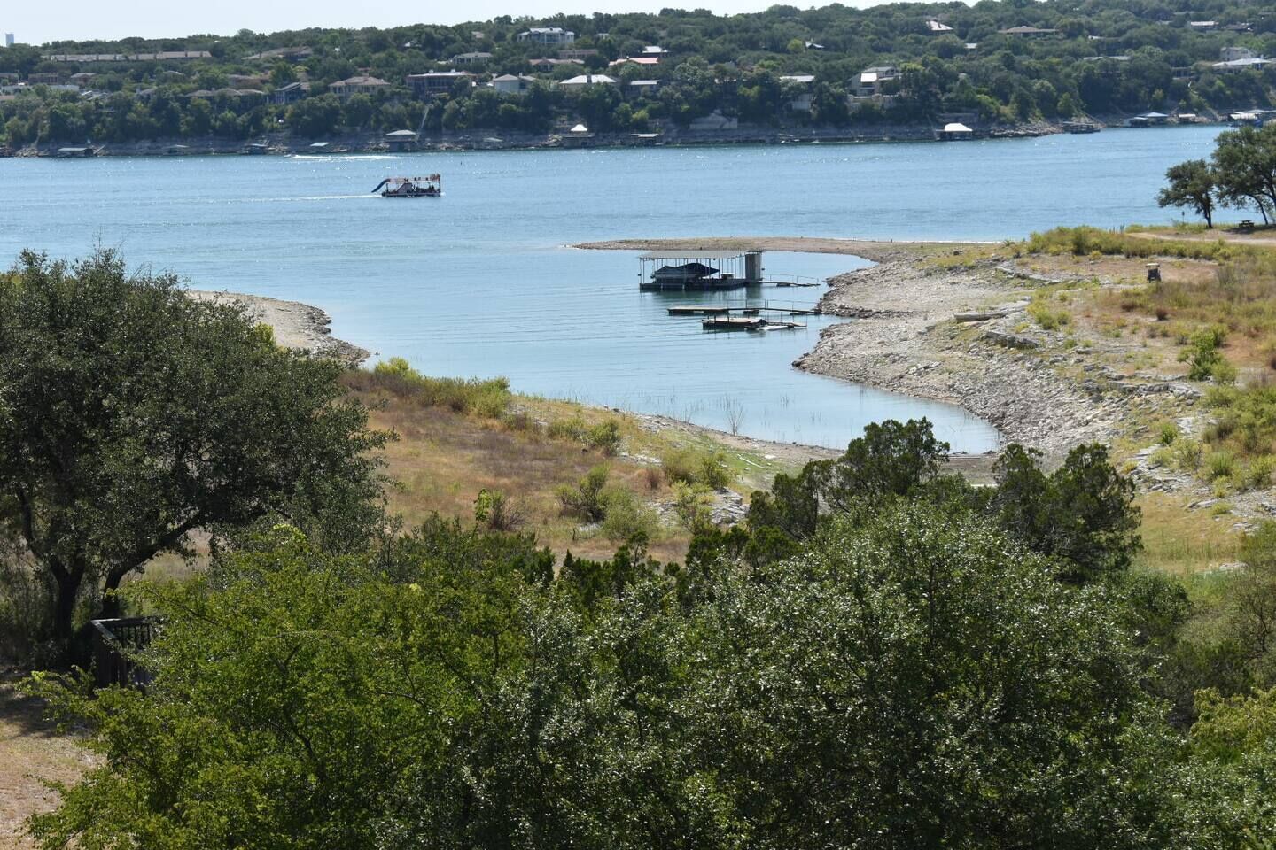 A river with boats, a dock, and a forested area.