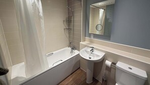 Une salle de bain moderne équipée d’une baignoire, d’un lavabo, de toilettes et d’un miroir.