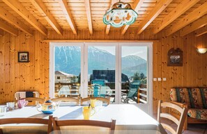 A wooden interior with a dining table, chairs, and a view of mountains through large windows. - Le Noyeray - Montagne - Proche Annecy (Faverges-Seythenex)