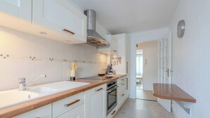 A modern kitchen with white cabinets, a wooden countertop, stainless steel appliances, and a built-in oven. - Le Vigny – 24h du Mans – Wifi (Le Mans)
