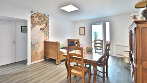 Un coin repas avec une table et des chaises en bois, un grand miroir et un tableau accroché au mur.