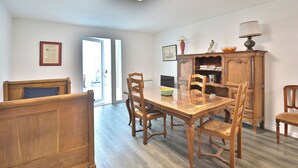 Un coin repas avec une table et des chaises en bois, un meuble contenant des livres et des objets décoratifs, et un certificat encadré accroché au mur.