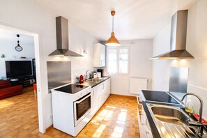Una cocina moderna con armarios blancos, encimera negra, electrodomésticos de acero inoxidable y suelo de madera.