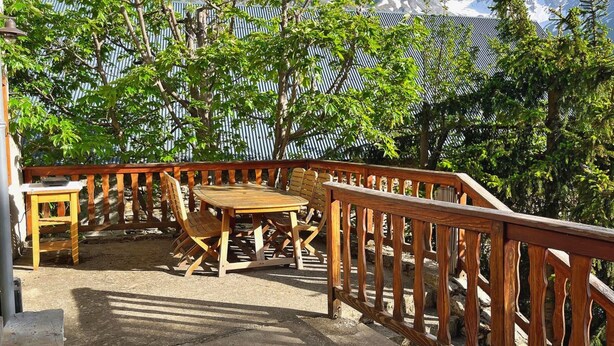 A wooden deck with a table and chairs, surrounded by a metal fence, overlooking a mountainous landscape. - Le Villard - Montagne - Wifi (VILLARD REYMOND)