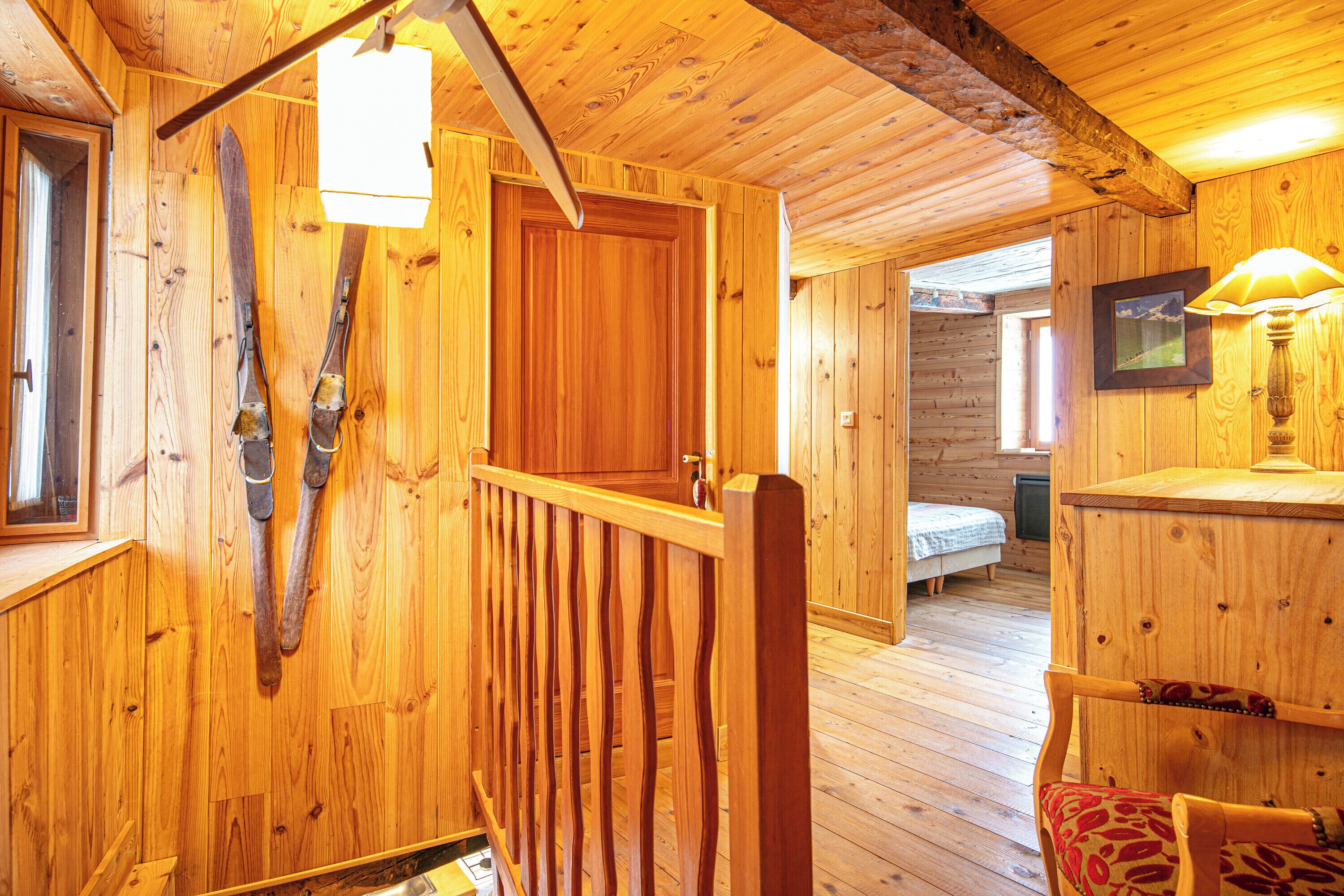A wooden interior with a staircase, a bed, and a desk area.