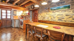A rustic kitchen with wooden beams, a stone wall, and a wooden dining table with chairs. - Le Villard - Montagne - Wifi (VILLARD REYMOND)