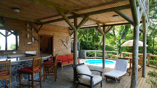 Une terrasse en bois avec une piscine, un espace bar et des sièges.