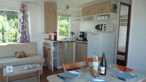A compact kitchen with a dining area, a sofa, and a window with curtains. - Cap - Confort 3 TV – 8p (2) (Plouézec)