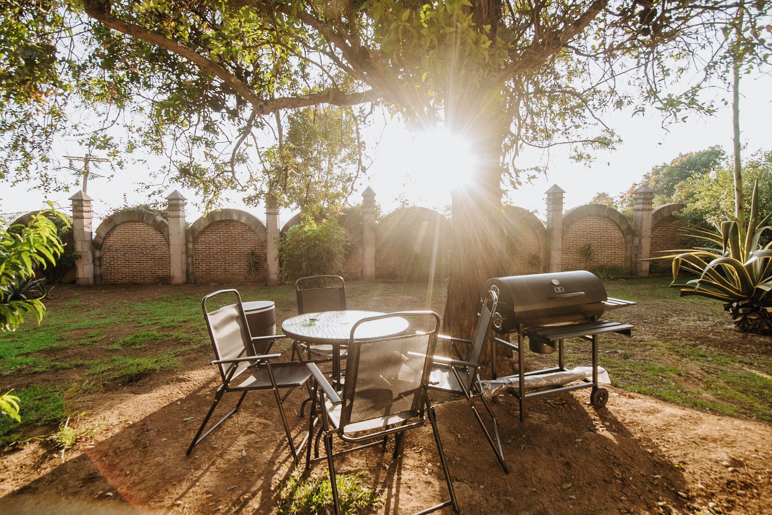 An outdoor patio with a round table, chairs, and a grill.