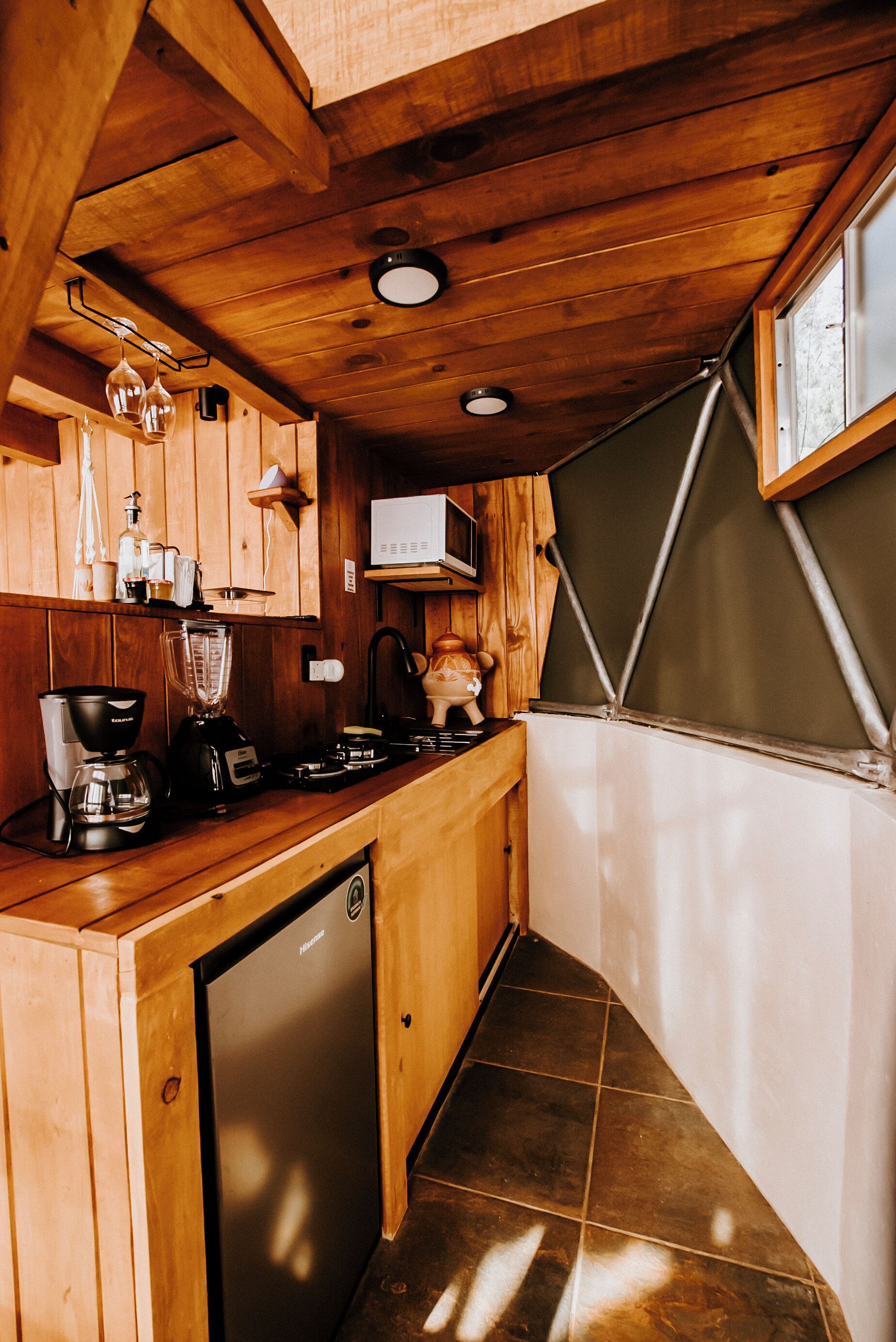 Een kleine keuken met houten kastjes, een inbouwvaatwasser en een klein aanrecht.