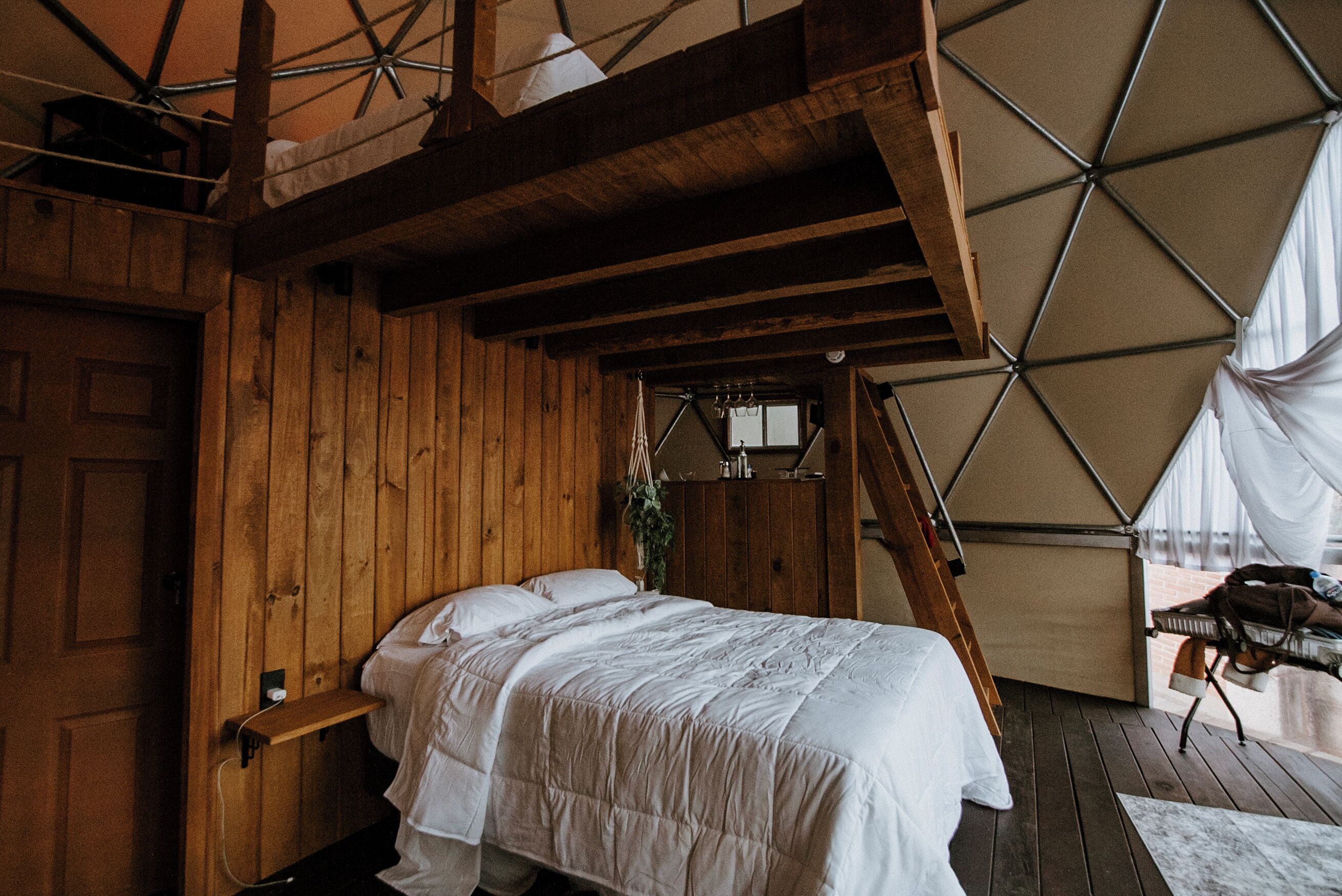 A tented accommodation with a bed, wooden walls, and a view of the outdoors.