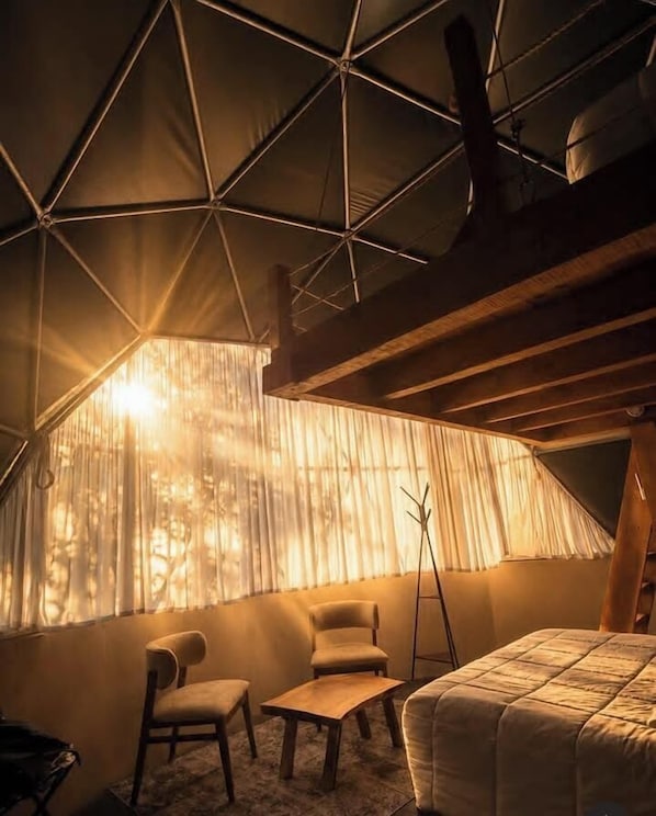 A tented room with a bed, two chairs, a table, and a window with curtains. - LUMBAI GLAMPING MAZAMITLA (Mazamitla)