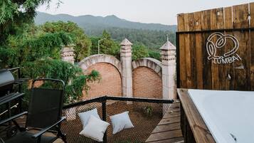 A wooden deck with a hot tub, a grill, and a hammock with pillows.