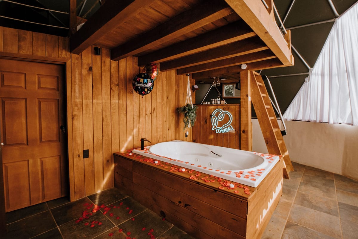 Un cuarto de spa de madera con una bañera grande, paredes de madera, una escalera y un letrero de neón.