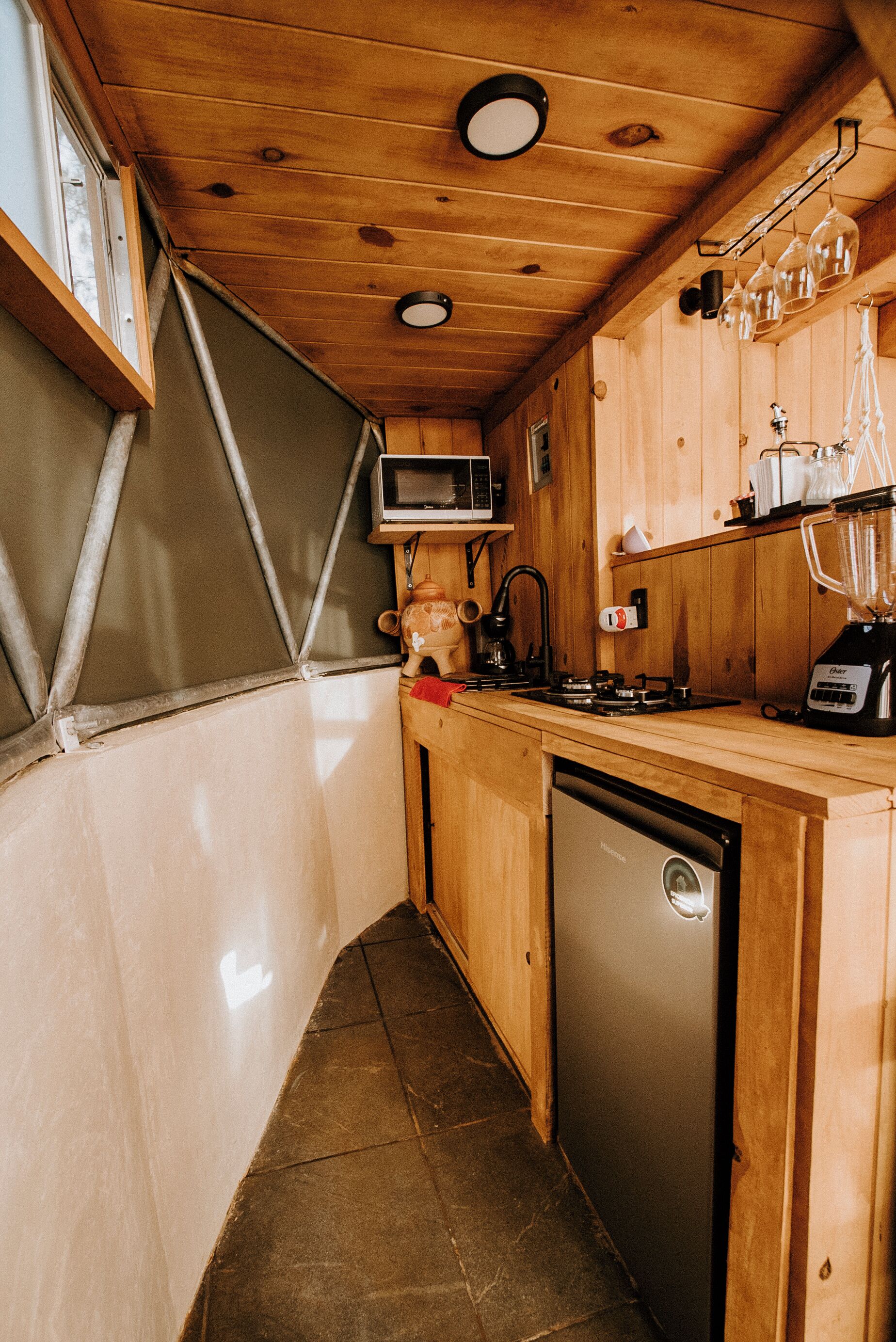 A compact kitchen with wooden cabinets, a microwave, a blender, and a dishwasher.