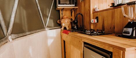 Uma cozinha compacta com armários de madeira, micro-ondas, liquidificador e máquina de lavar louça.