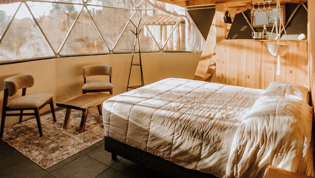 A tented room with a bed, chairs, a ladder, and a window. - LUMBAI GLAMPING MAZAMITLA (Mazamitla)