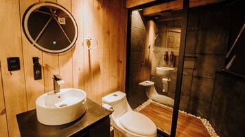 A wooden bathroom with a round mirror, a sink, and a toilet.