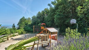 A playground with a basketball hoop and a climbing structure, surrounded by sand and greenery. - Cap - Confort 3 TV – 8p (5) (Plouézec)