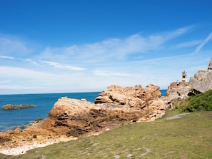 A coastal landscape with rocky terrain, a grassy area, and a lighthouse. - Cap - Confort 2 TV - 4/5p (Plouézec)