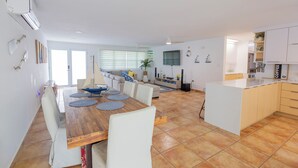 A spacious kitchen with a dining area, featuring a wooden table and chairs, a built-in island, and modern appliances.
