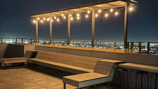 Une terrasse sur le toit, dotée d’un espace salon, d’un bar et d’une guirlande lumineuse.