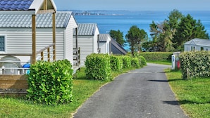 En rad vita, flyttbara hus med grå tak, en asfalterad väg och utsikt över havet.