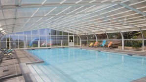 An indoor swimming pool with a glass ceiling, clear water, and several lounge chairs. - Cap - Confort 2 TV - 4/5p (9) (Plouézec)