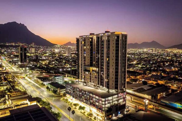 A high-rise hotel with multiple floors, surrounded by a cityscape at dusk. - Modern Executive Loft Express / Private Parking Space (Monterrey)