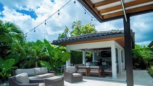 An outdoor patio area with wicker furniture, a covered seating area, and a view of the surrounding lush greenery. - Greenview Villa/Luxury Heated Pool Home Golf View (Miami)