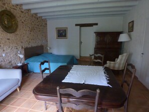 Ein Schlafzimmer mit einem Bett, einem Holztisch mit Spitzenleinentuch, einem Stuhl, einer Couch und einem Schrank.