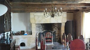 Ein rustikaler Essraum mit Kamin aus Stein, Holzmöbeln und einer Chandelier.