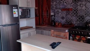 Una cocina compacta con un refrigerador de acero inoxidable, un microondas y una estufa a gas.