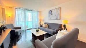 Uma sala de estar moderna com sofá, poltrona, mesa de centro e abajur.