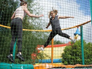 Cercado para trampolín con red, una red de seguridad y una estructura inflable colorida al fondo.
