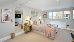 Ein Schlafzimmer mit einem großen Bett, Nachttischen, einem Spiegel und Bildern an den Wänden.