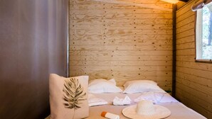 Ein Holzhüttenraum mit einem Bett, Kissen, einem Hut und einer Flasche.