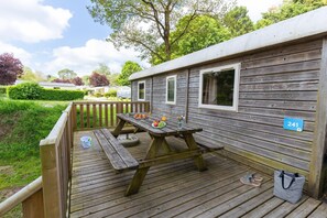 A wooden deck with picnic tables, a number sign, and a bag. - Bréhadour - Roulotte - 4p (Guérande)