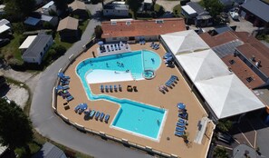An aerial view of a residential area with a swimming pool surrounded by lounge chairs and umbrellas, indicating a recreational facility. - Gildas - Privilège 4 - 8p (Préfailles)