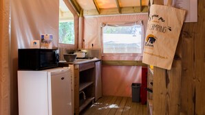 Eine kleine Küche mit Mikrowelle, Herd und Spüle, Holzschränken und einem Fenster mit Aussicht.