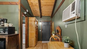 Una cocina compacta con armarios de madera, microondas y una mesa de comedor con sillas.