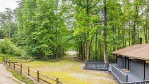 A wooden cabin with a porch, surrounded by a fenced area and dense trees. - The Lost Compass - Suite #2 - Cozy Cabin Retreat (Sautee Nacoochee)