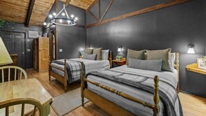 A cozy bedroom with two beds, wooden beams, a chandelier, and a small table. - The Lost Compass - Suite #2 - Cozy Cabin Retreat (Sautee Nacoochee)