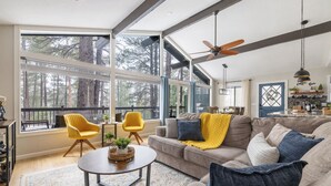 A spacious living room with a large window, a ceiling fan, and a cozy seating area with a sofa and armchairs. - Modern Cabin Retreat w/ Deck & BBQ (Flagstaff)