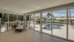 Amplia habitación con ventanas grandes, piscina y una silla con almohada de estrella de mar.