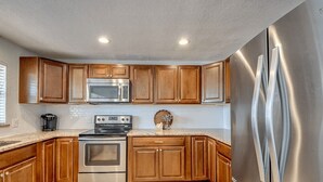 Una cocina con armarios de madera, electrodomésticos de acero inoxidable y encimera de granito.